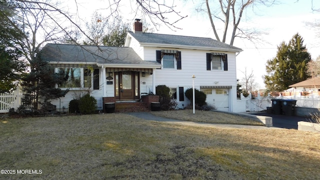 split level home featuring roof with shingles, fence, a chimney, and a front lawn