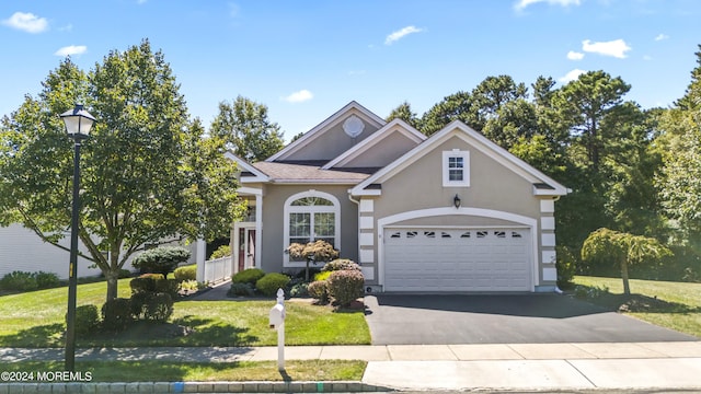 traditional home featuring aphalt driveway, a front yard, an attached garage, and stucco siding