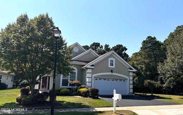 traditional-style house featuring aphalt driveway, a front yard, an attached garage, and stucco siding