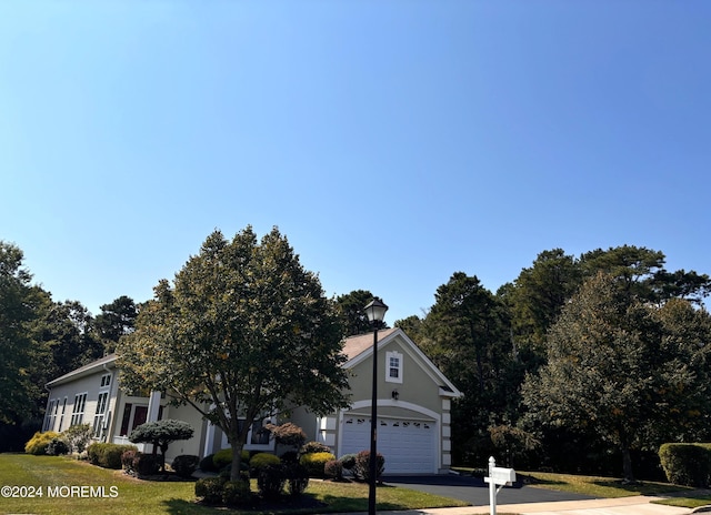 obstructed view of property with an attached garage, a front lawn, and aphalt driveway