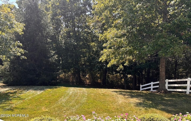 view of yard featuring a forest view and fence