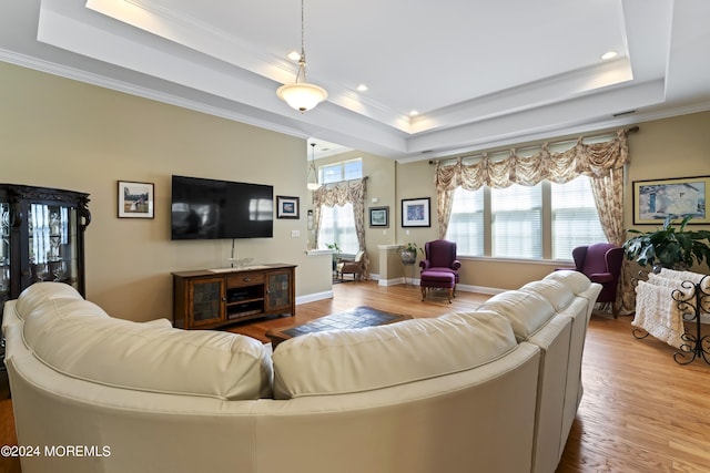 living room with a tray ceiling, crown molding, and wood finished floors