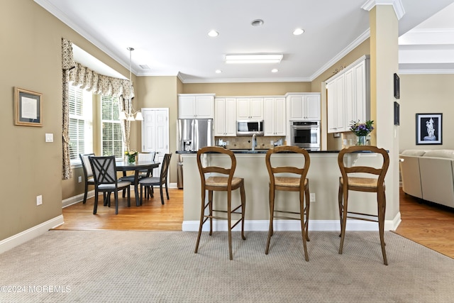 kitchen with stainless steel appliances, white cabinetry, a kitchen breakfast bar, dark countertops, and crown molding