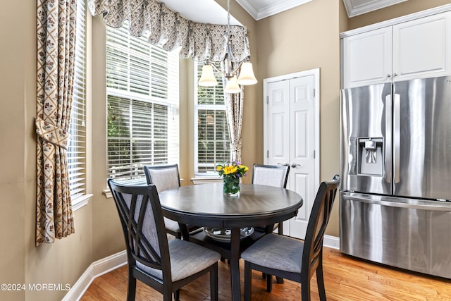 dining area with light wood-style floors, baseboards, and ornamental molding