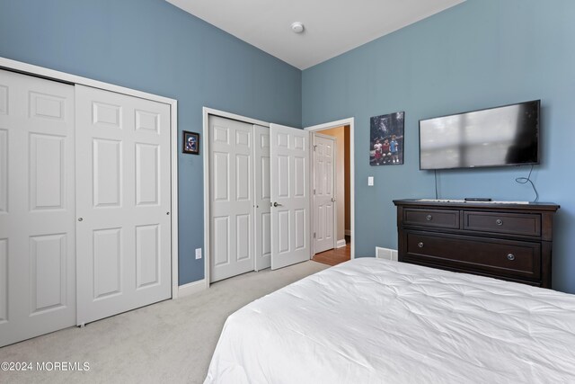 carpeted bedroom featuring baseboards and multiple closets