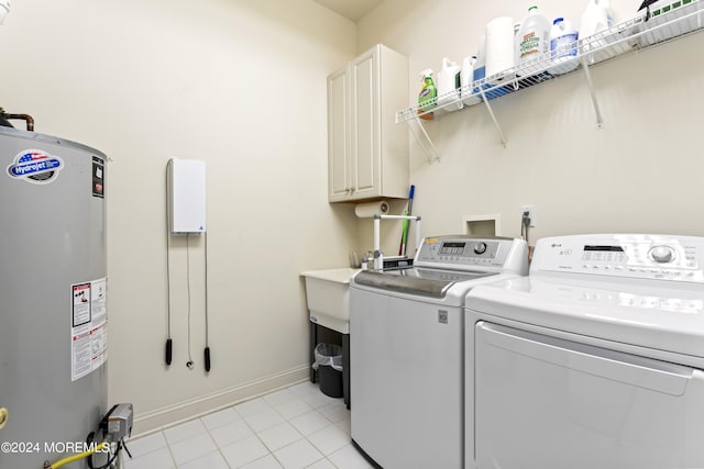 laundry area featuring light tile patterned floors, baseboards, water heater, cabinet space, and washer and clothes dryer