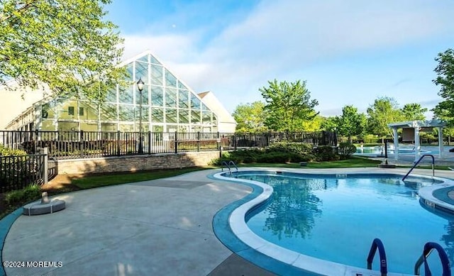 pool featuring fence and a pergola