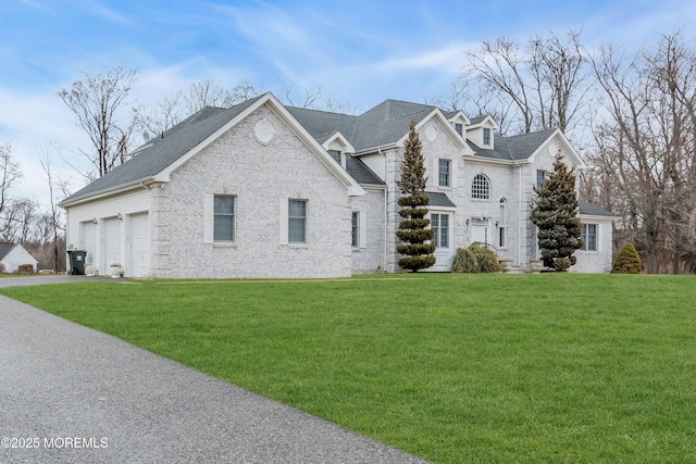 view of front of house featuring a garage, a front yard, brick siding, and driveway