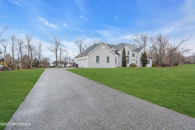 view of front of home with a garage, gravel driveway, and a front lawn