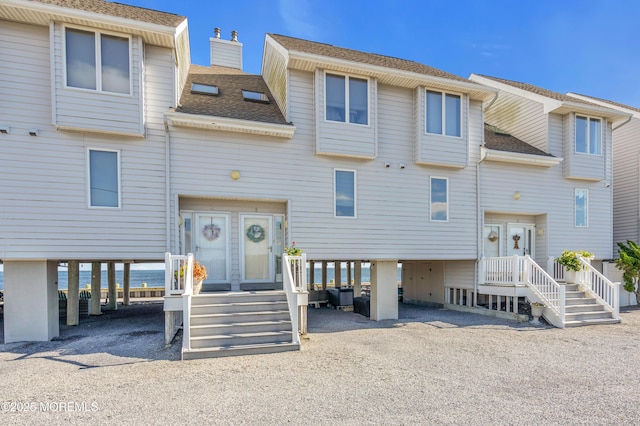 townhome / multi-family property featuring driveway, a chimney, a carport, and roof with shingles