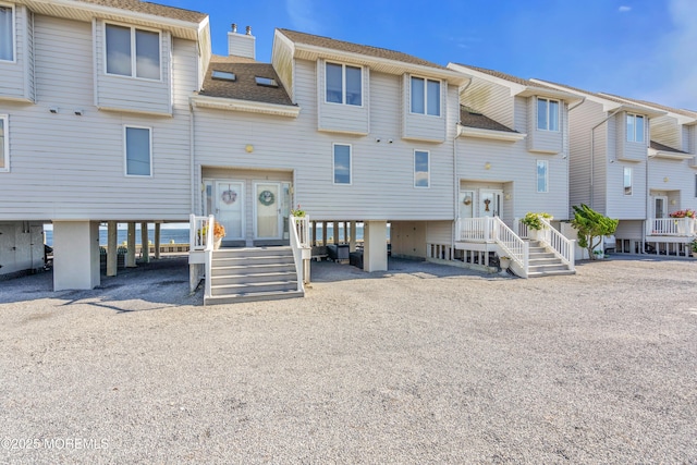 townhome / multi-family property with a carport, a residential view, a shingled roof, and dirt driveway