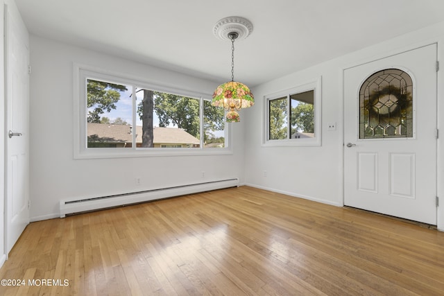 interior space featuring a baseboard heating unit, light wood-style flooring, and baseboards