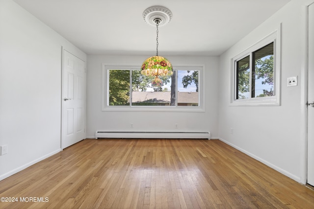 unfurnished dining area featuring a baseboard heating unit, light wood-style flooring, and baseboards