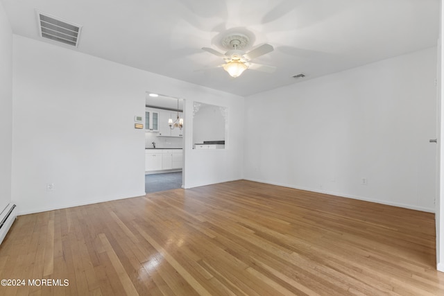 unfurnished living room featuring light wood finished floors, baseboards, visible vents, and ceiling fan with notable chandelier