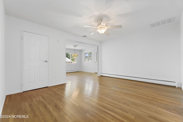 spare room featuring visible vents, baseboard heating, a baseboard heating unit, a ceiling fan, and light wood-type flooring