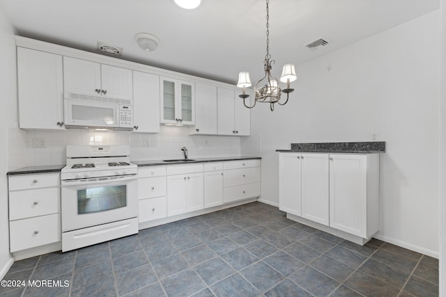 kitchen featuring dark countertops, white appliances, a sink, and backsplash