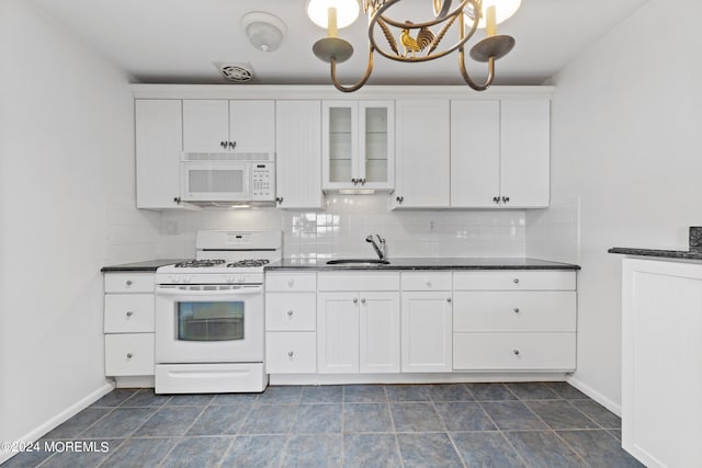 kitchen featuring dark countertops, white appliances, decorative backsplash, and a sink