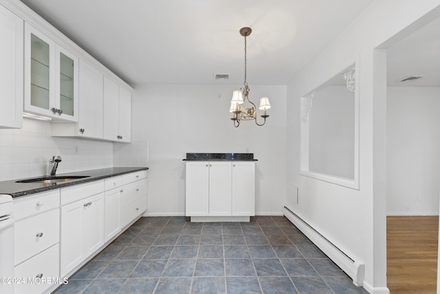 kitchen with dark countertops, backsplash, a baseboard heating unit, glass insert cabinets, and a sink