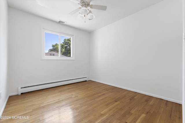 unfurnished room featuring baseboards, baseboard heating, visible vents, and light wood-style floors