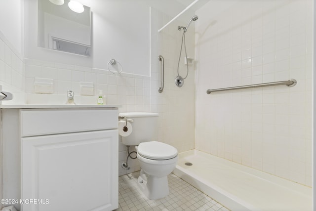 bathroom featuring tile walls, toilet, a tile shower, vanity, and tile patterned floors