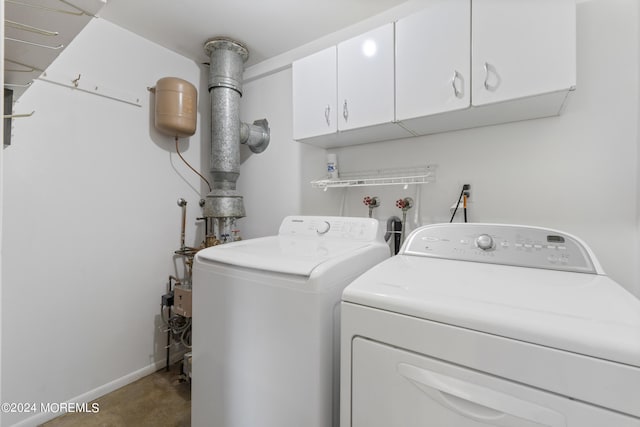 washroom featuring independent washer and dryer, cabinet space, and baseboards