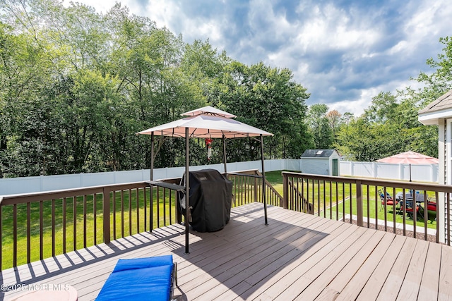 wooden deck with an outbuilding, a yard, a storage unit, and area for grilling