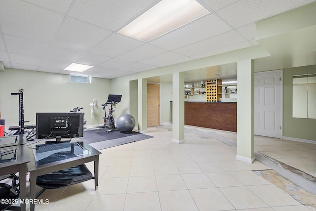 exercise room featuring light tile patterned floors, baseboards, and a drop ceiling