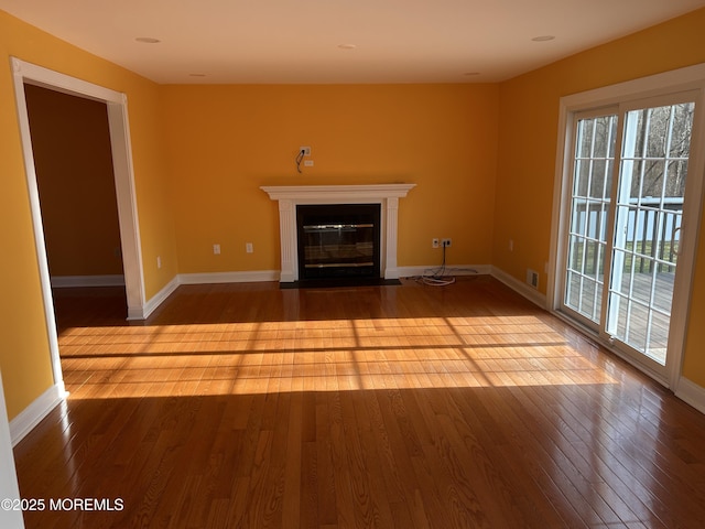 unfurnished living room with wood-type flooring, a fireplace with flush hearth, and baseboards