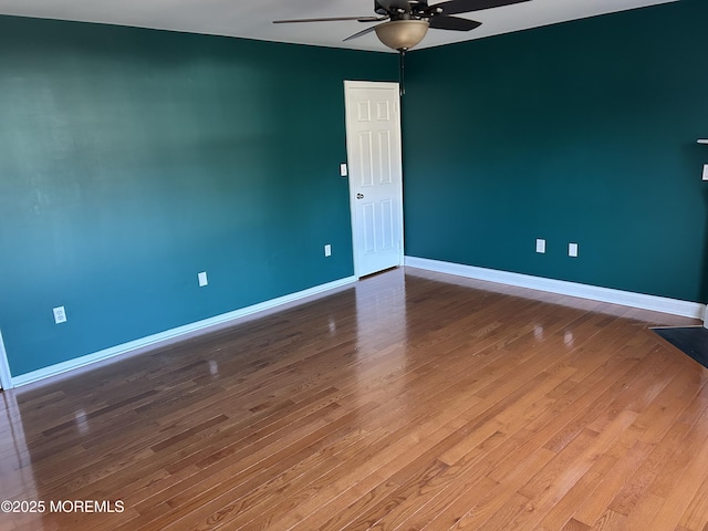 empty room featuring ceiling fan, baseboards, and wood finished floors