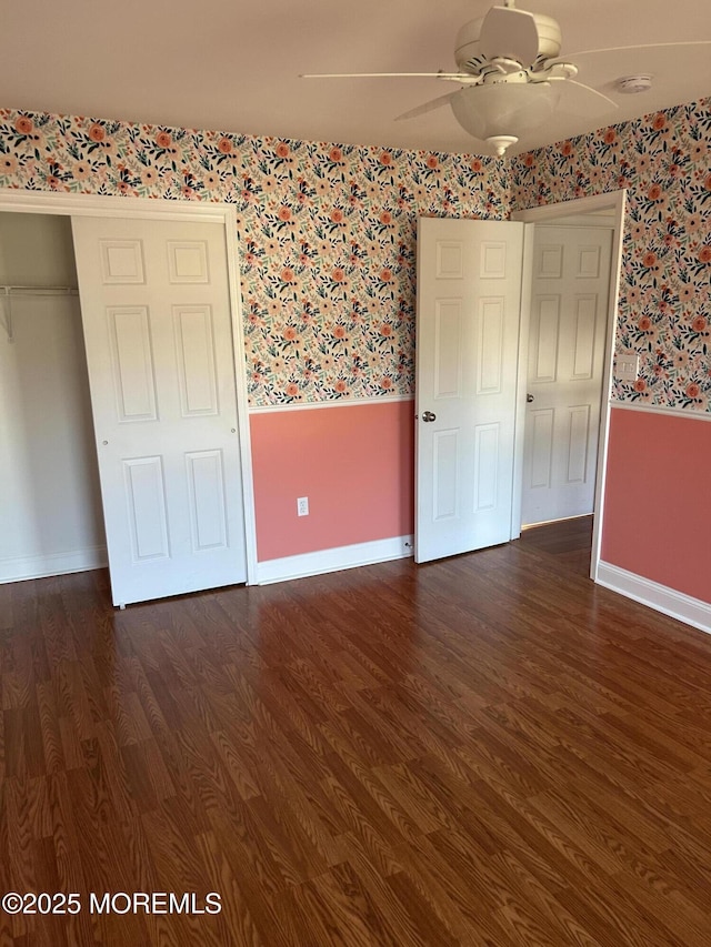 unfurnished bedroom with wallpapered walls, baseboards, dark wood-style flooring, and wainscoting