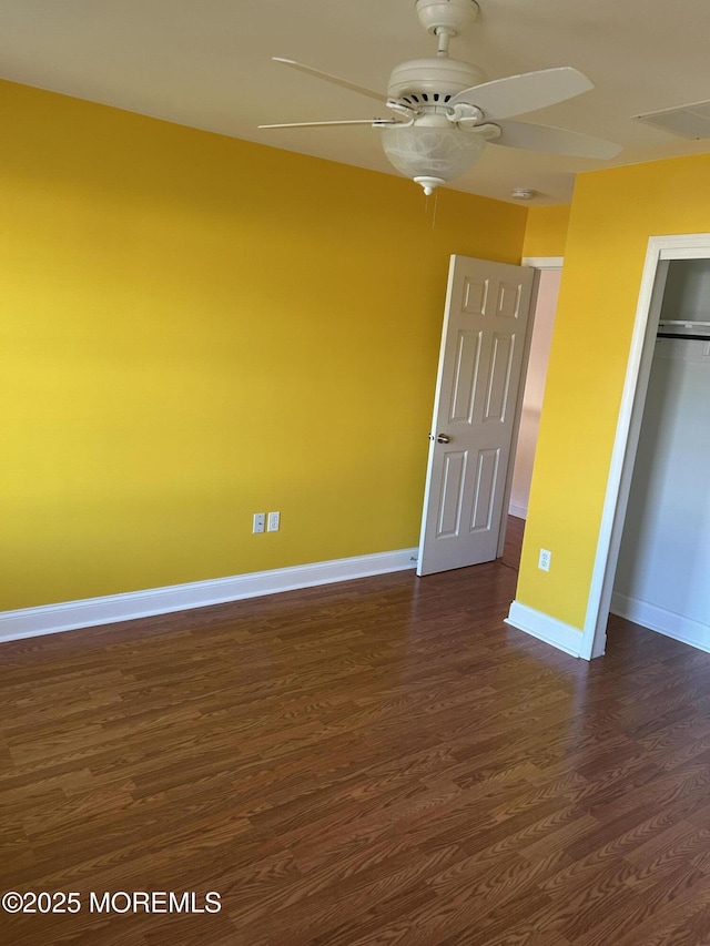 unfurnished bedroom featuring dark wood finished floors, a closet, visible vents, a ceiling fan, and baseboards