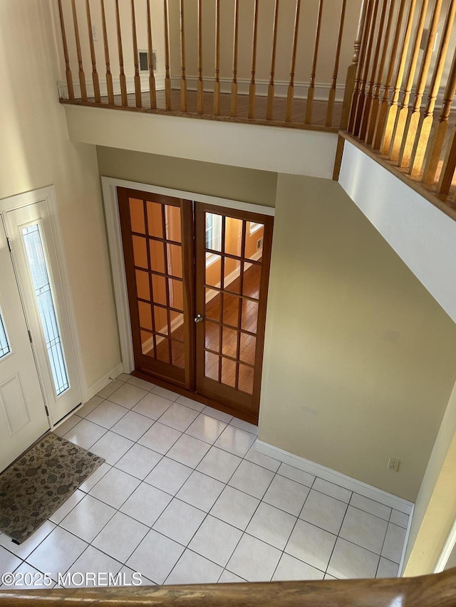 interior space featuring light tile patterned floors, baseboards, a high ceiling, and visible vents