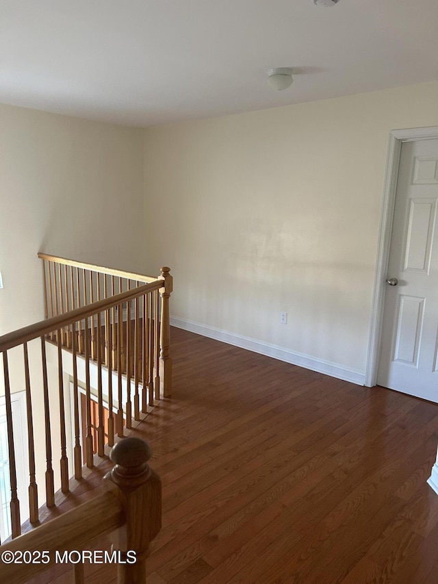 interior space featuring dark wood-style flooring, an upstairs landing, and baseboards