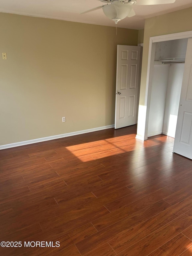 unfurnished bedroom with ceiling fan, dark wood-style flooring, a closet, and baseboards