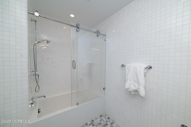 bathroom with shower / bath combination with glass door and tile walls