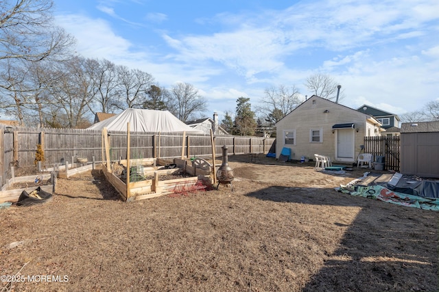 view of yard featuring an outbuilding, a fenced backyard, a storage shed, and a vegetable garden