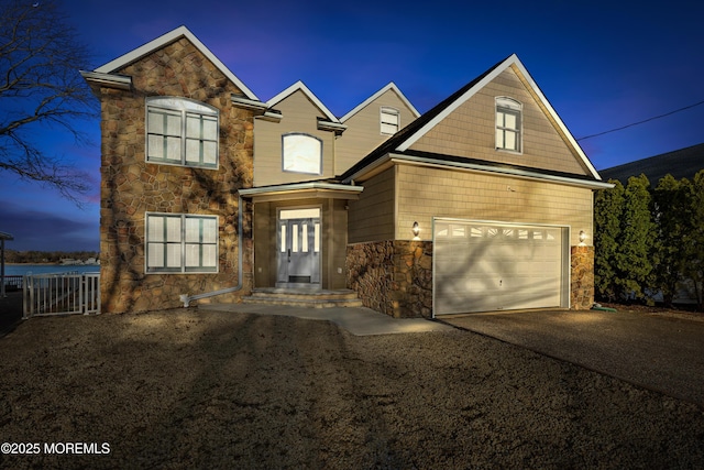 traditional home with aphalt driveway, stone siding, fence, and a garage