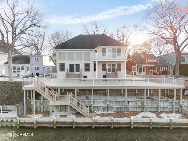 rear view of property with stairs and a water view