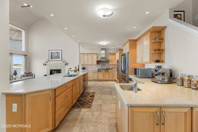 kitchen featuring stainless steel appliances, light brown cabinets, a sink, and wall chimney exhaust hood