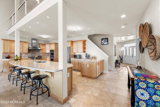 kitchen with open shelves, appliances with stainless steel finishes, a sink, a large island with sink, and wall chimney exhaust hood