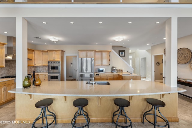 kitchen featuring light brown cabinets, appliances with stainless steel finishes, a sink, and tasteful backsplash