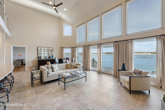 living room with a water view, a high ceiling, a ceiling fan, and recessed lighting