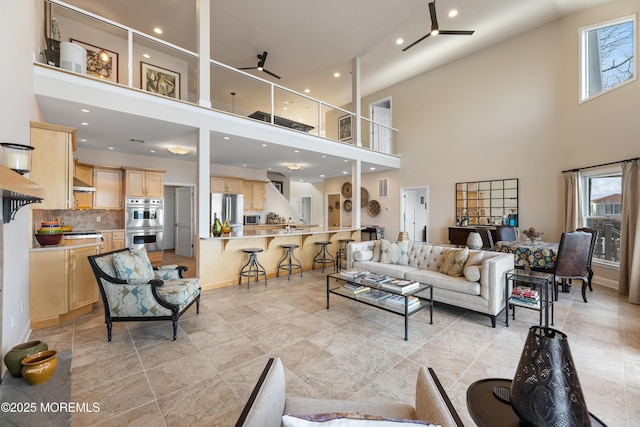 living room featuring ceiling fan, a high ceiling, and a healthy amount of sunlight