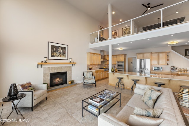 living room with a tile fireplace, a towering ceiling, baseboards, and recessed lighting