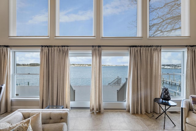 interior space featuring a water view, a towering ceiling, and tile patterned floors