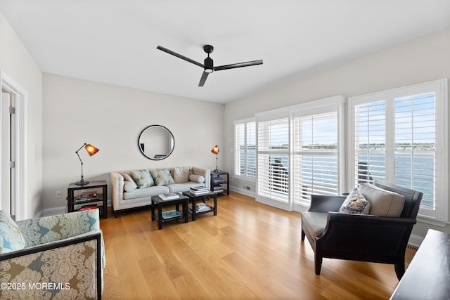 living area with ceiling fan, baseboards, and light wood-style floors