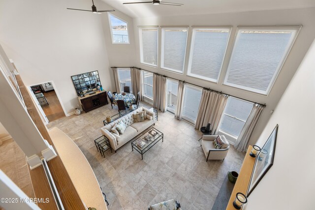 living area with a ceiling fan, baseboards, and a high ceiling