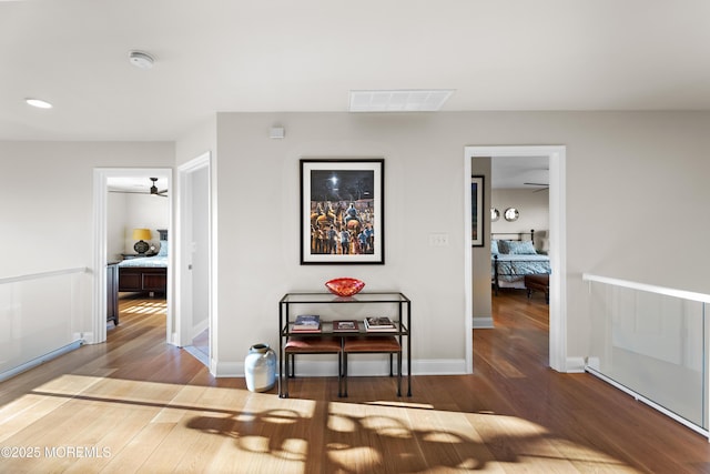 hall featuring baseboards, visible vents, and wood finished floors