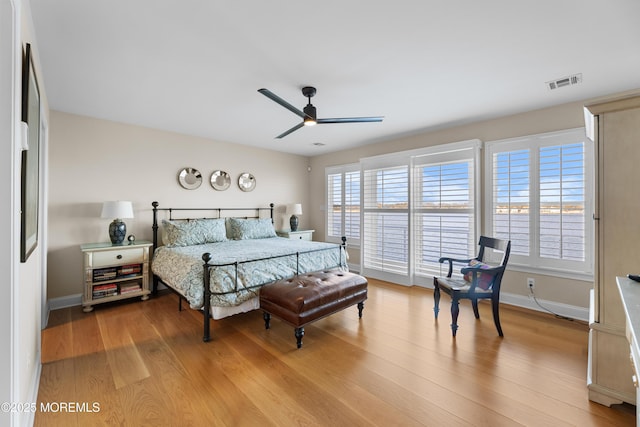 bedroom featuring a ceiling fan, visible vents, baseboards, and wood finished floors