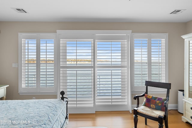 bedroom with light wood finished floors, baseboards, and visible vents